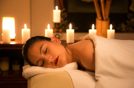 Bandeja con nenúfares rosas, piedras de spa, botellas, cucharas de madera y cuencos.