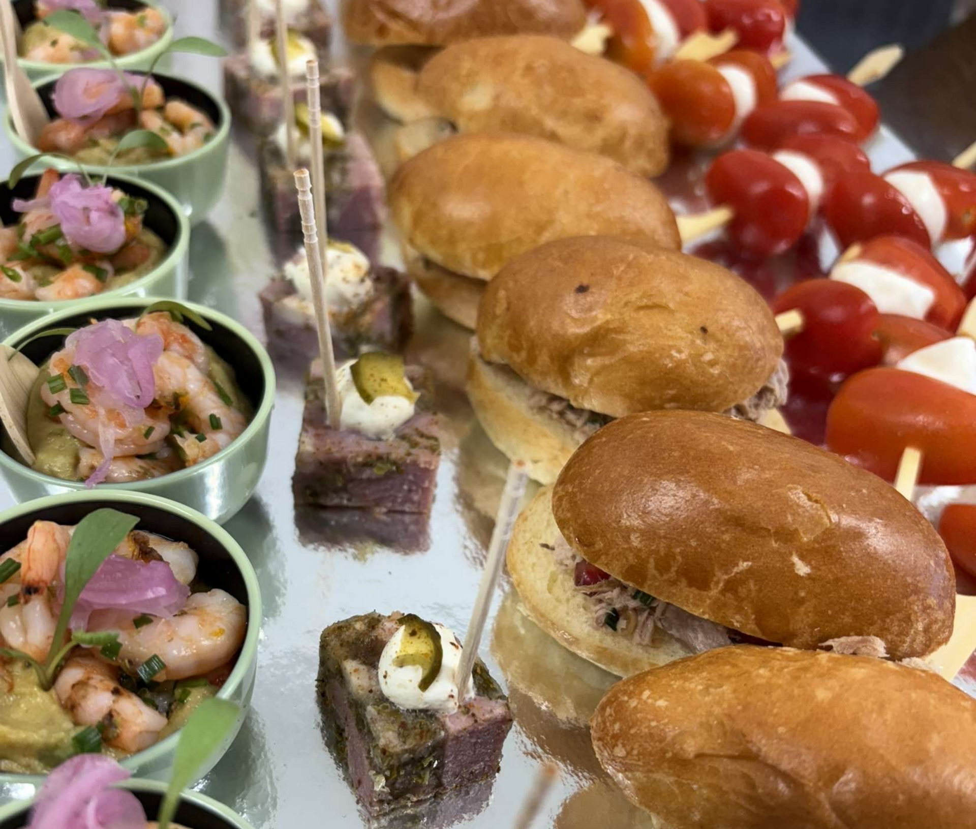 Entrées sur plateau d'argent : salade de crevettes, minisandwichs, brochettes de tomates et mozzarella.