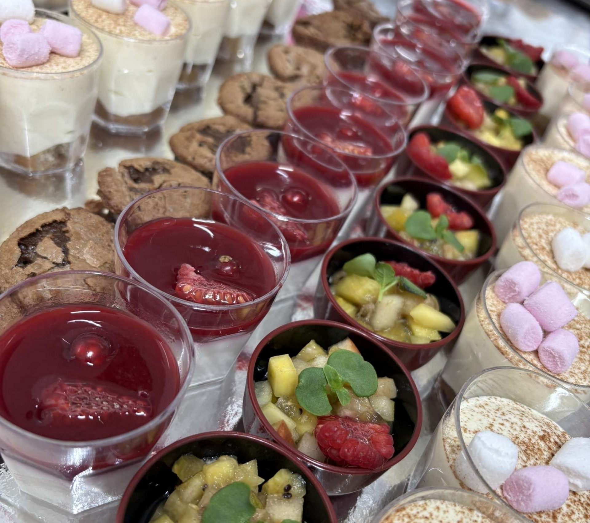 Bar à desserts avec diverses gourmandises sucrées : parfaits, biscuits, salade de fruits et coupes de gelée.