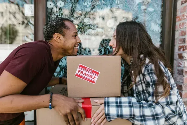 Un hombre y una mujer se miran mientras sostienen cajas.