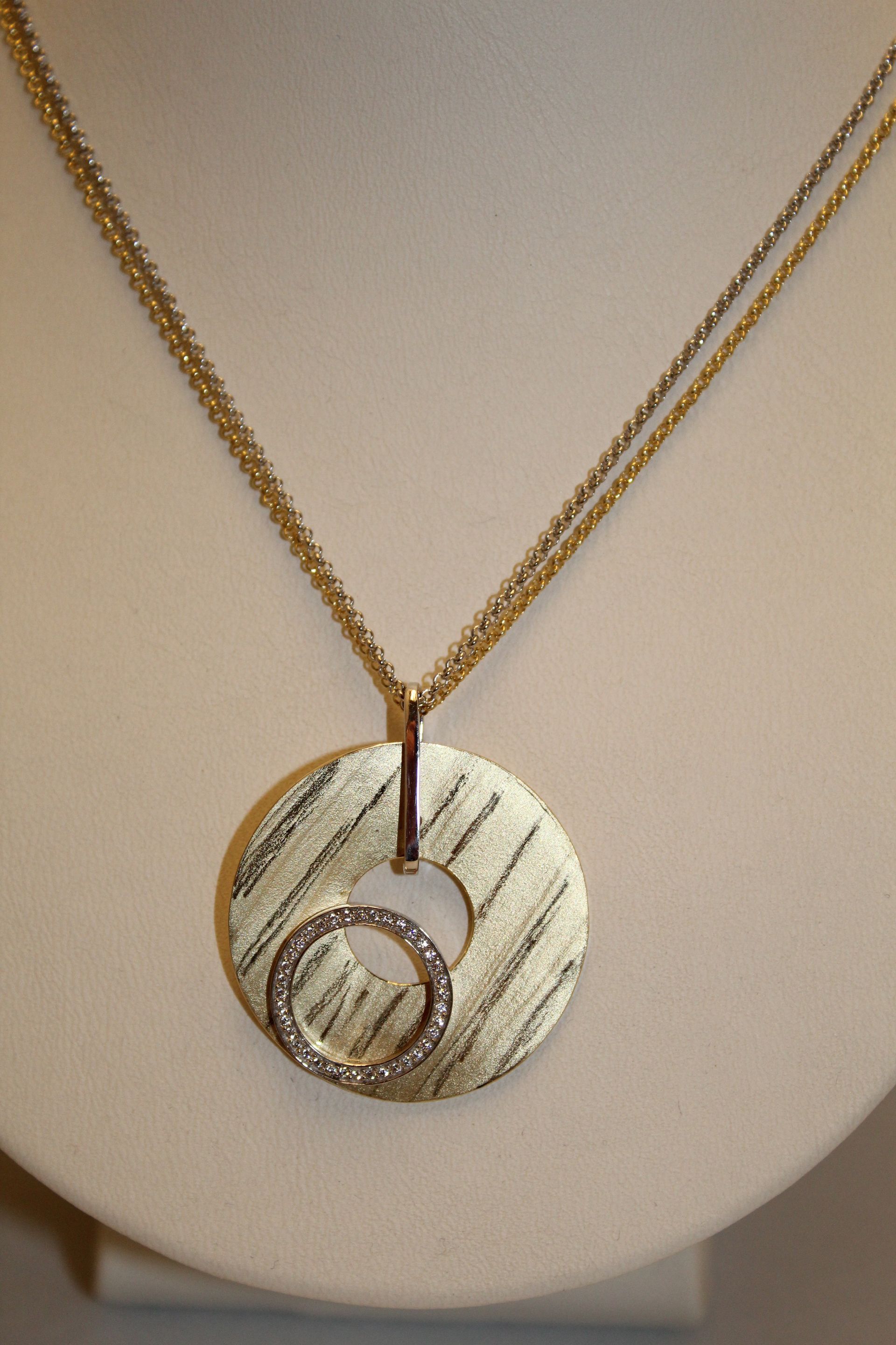 Vergoldete Silberkette mit einem großen runden Anhänger in Gold und einem kleinen Ring mit Diamanten besetzt