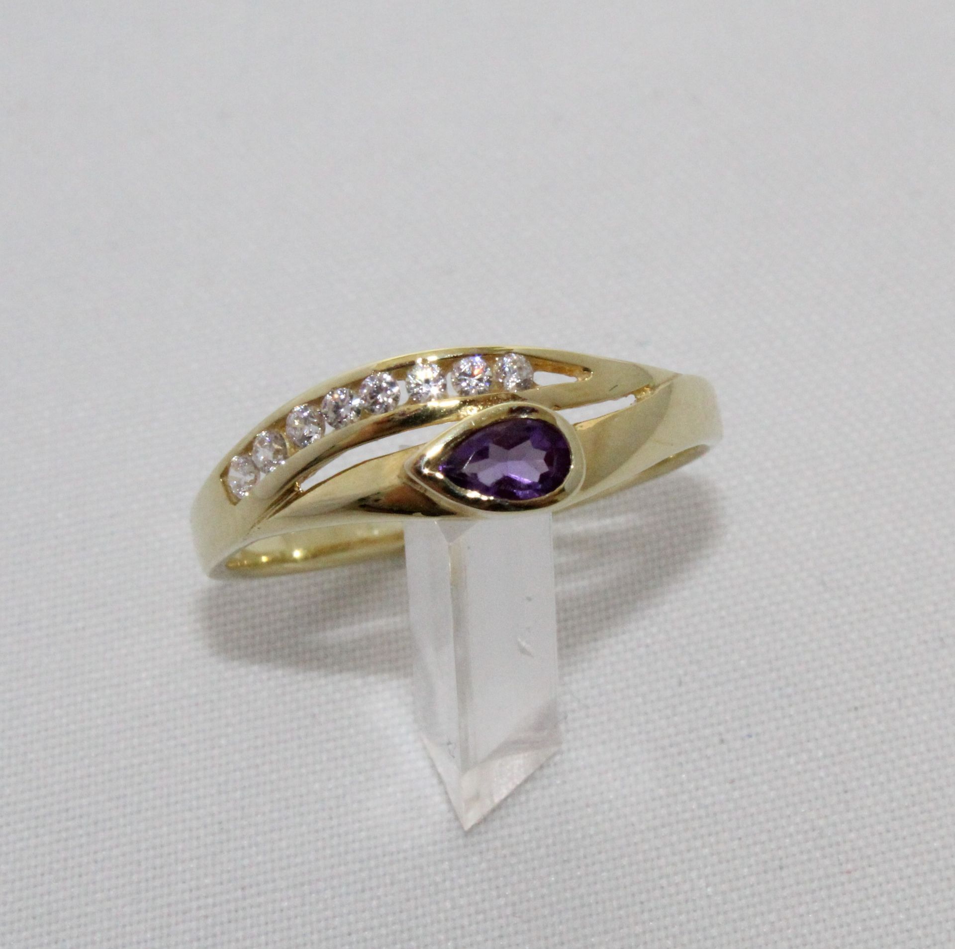 Goldener Ring mit kleinen Diamanten besetzt und einem Lila Edelstein in Tropfenform