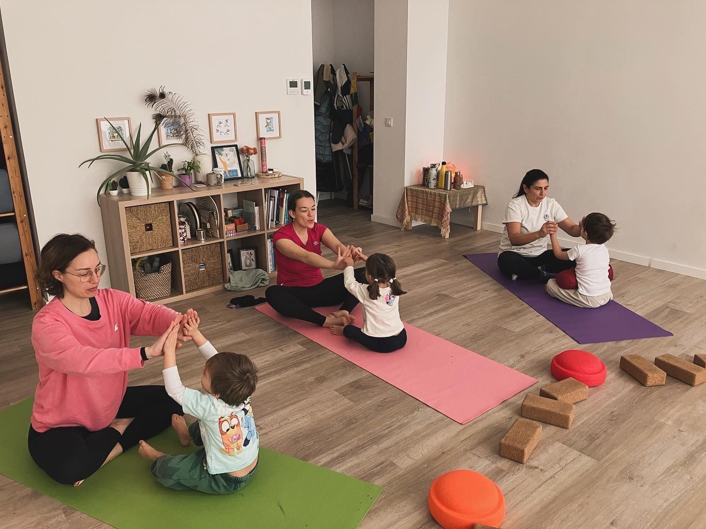 Adultos y niños practicando yoga en colchonetas. En interiores.