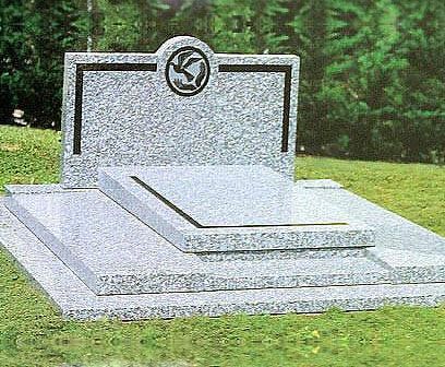 Pierre tombale en granit gris avec bordure noire et emblème circulaire, située dans un espace herbeux.