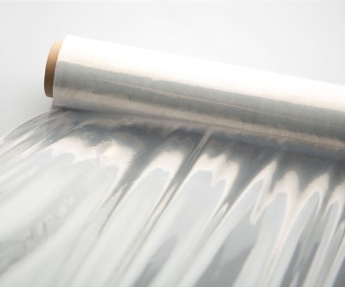Un rollo de envoltura de plástico transparente sobre una superficie blanca.