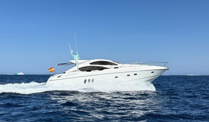 Un lujoso yate blanco surcando a toda velocidad el océano azul bajo un cielo despejado.