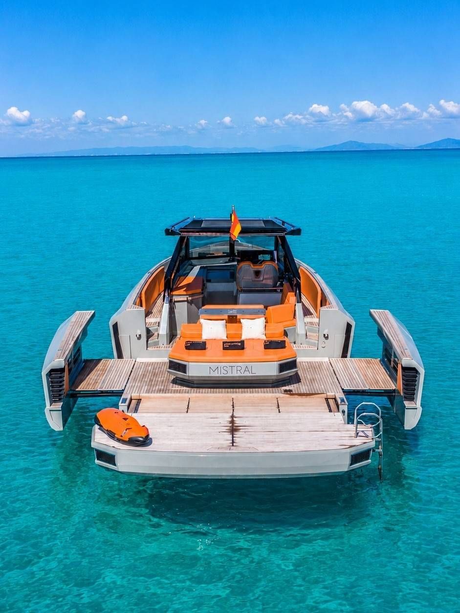 Un barco naranja y blanco flotando sobre aguas turquesas cristalinas bajo un cielo azul brillante.