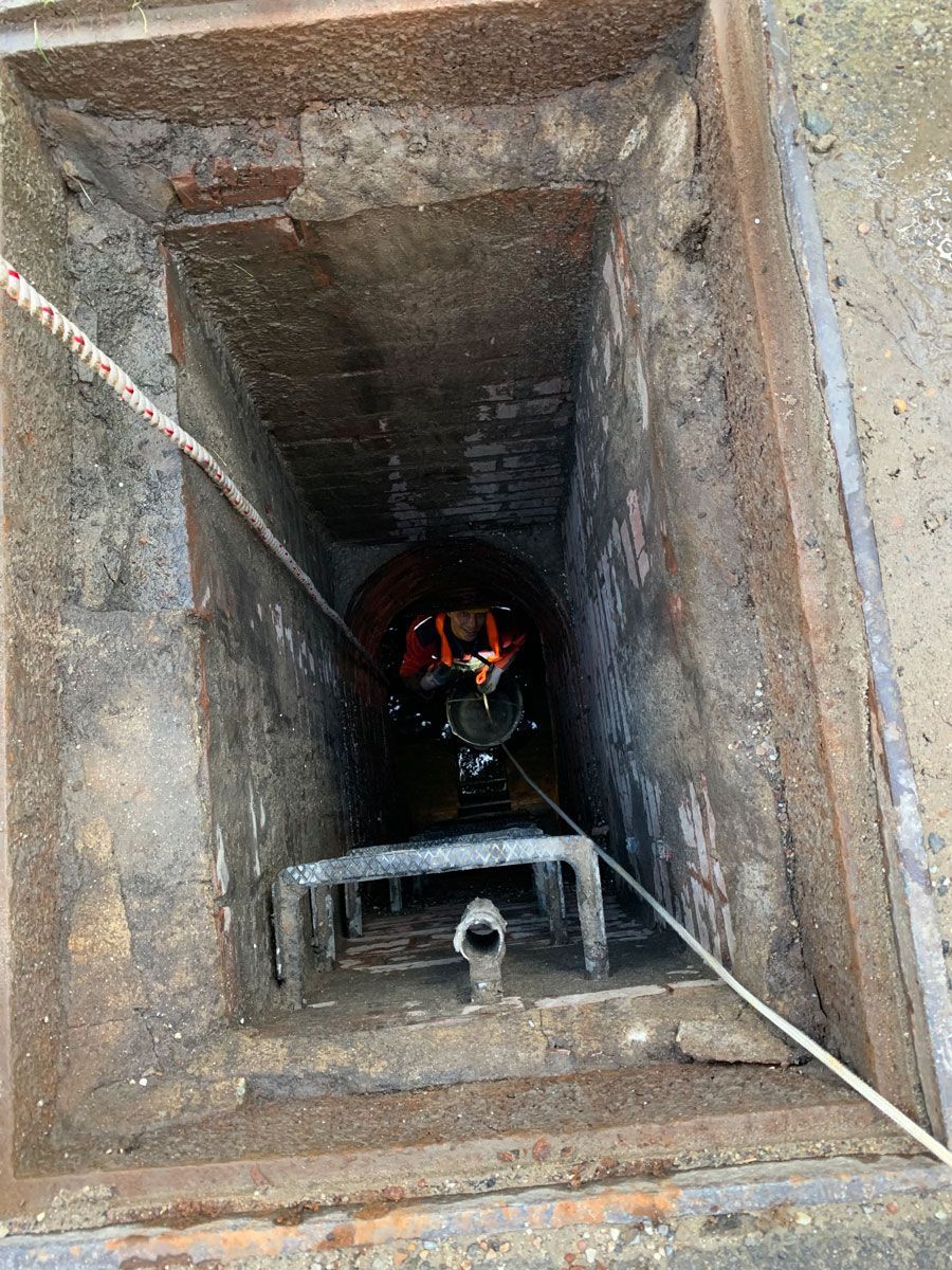 Ein Kanaldeckel, aus dem ein Schlauch herauskommt.