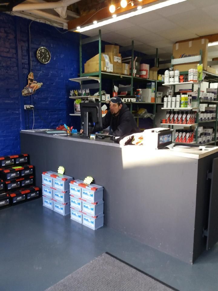 Comptoir avec employé, magasin avec étagères de marchandises ; piles au premier plan.