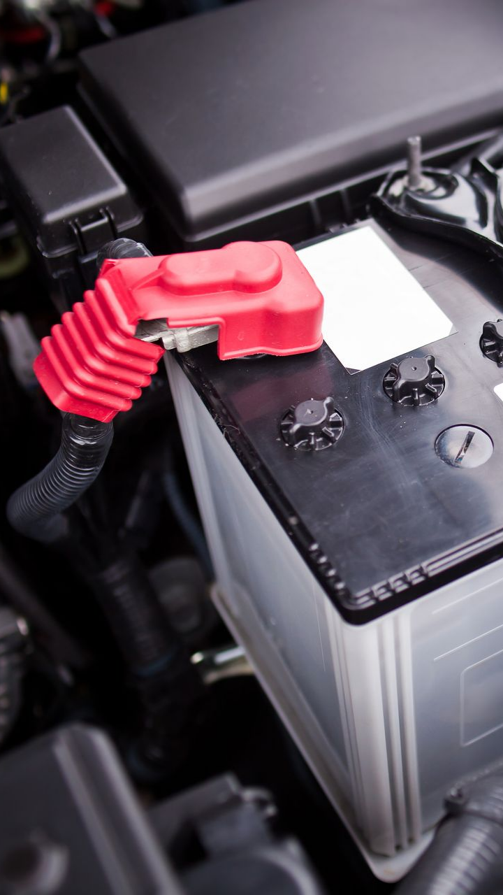 Borne positive rouge de la batterie connectée à une batterie de voiture dans un compartiment moteur.