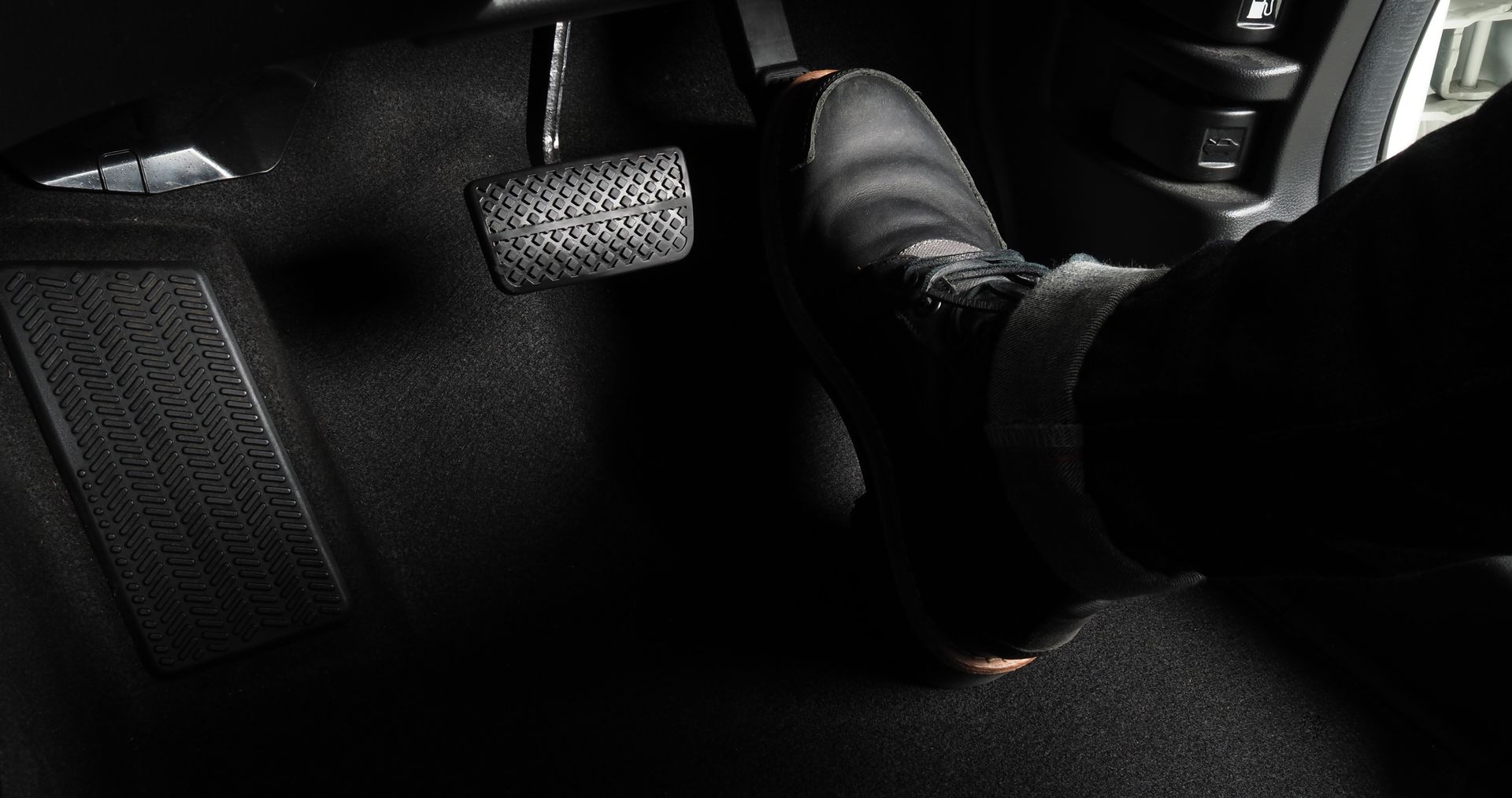 Pied appuyant sur la pédale de frein d'une voiture, à l'intérieur d'un véhicule.