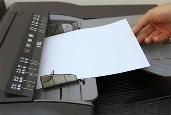 Una persona está sacando un trozo de papel de una impresora.