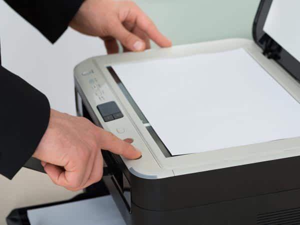 Una persona está usando una impresora para escanear una hoja de papel.