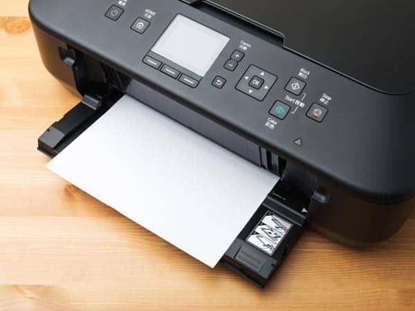 Una impresora negra está sentada sobre una mesa de madera.