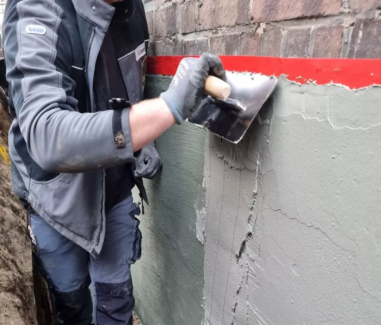 Ein Mann arbeitet mit einer Kelle an einer Ziegelwand