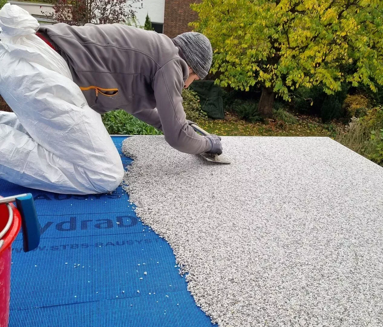 Ein Mann im Schutzanzug kniet auf einer blauen Matte.