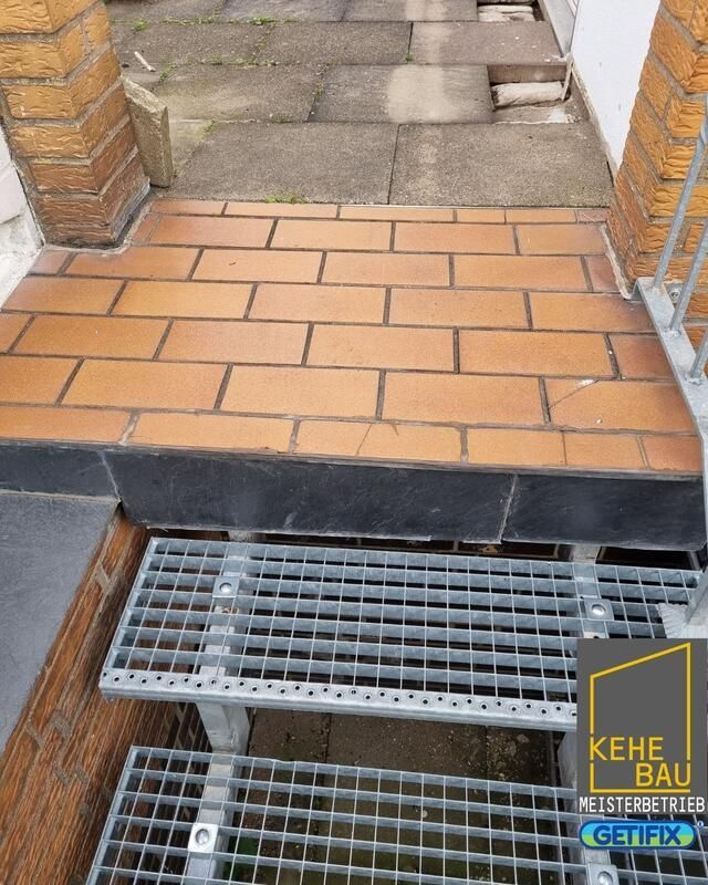 Eine Metalltreppe, die zu einem gemauerten Gehweg hinaufführt