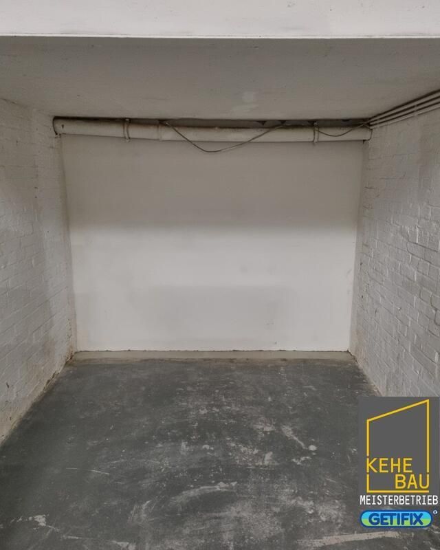 Eine leere Garage mit einer weißen Wand und einem grauen Boden.