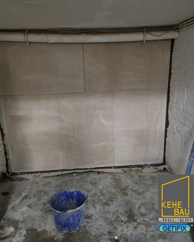 Ein Eimer Zement steht neben einer Wand auf dem Boden.