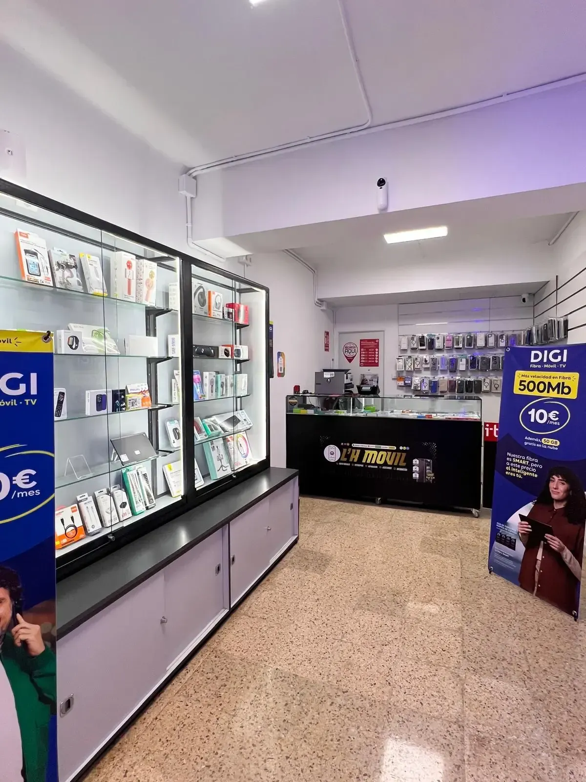 Vista interior de una tienda de telefonía con vitrinas, mostrador y anuncios de DIGI.