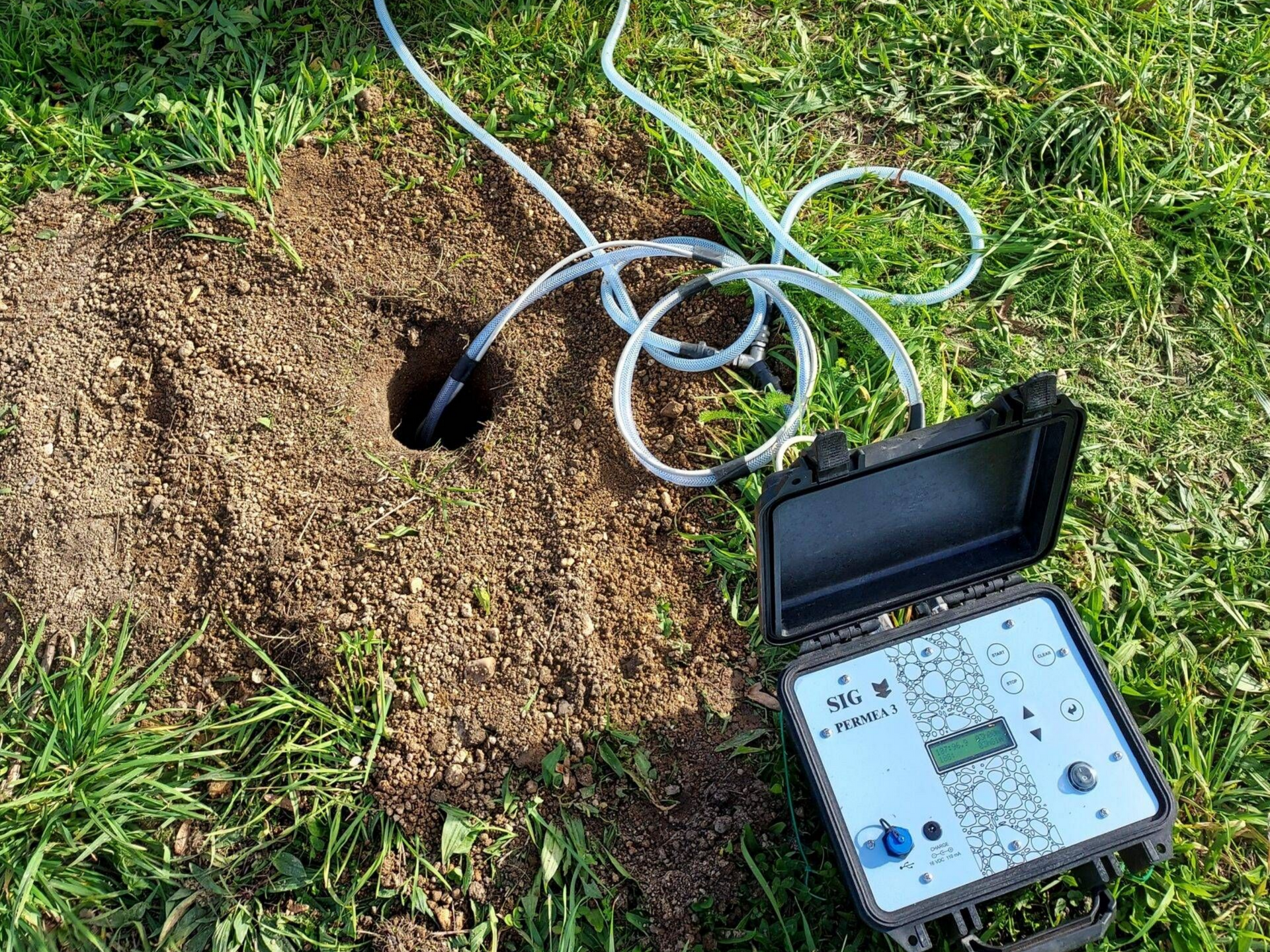 Un boîtier noir avec des tubes reliés à un trou dans le sol pour effectuer des tests de sol.