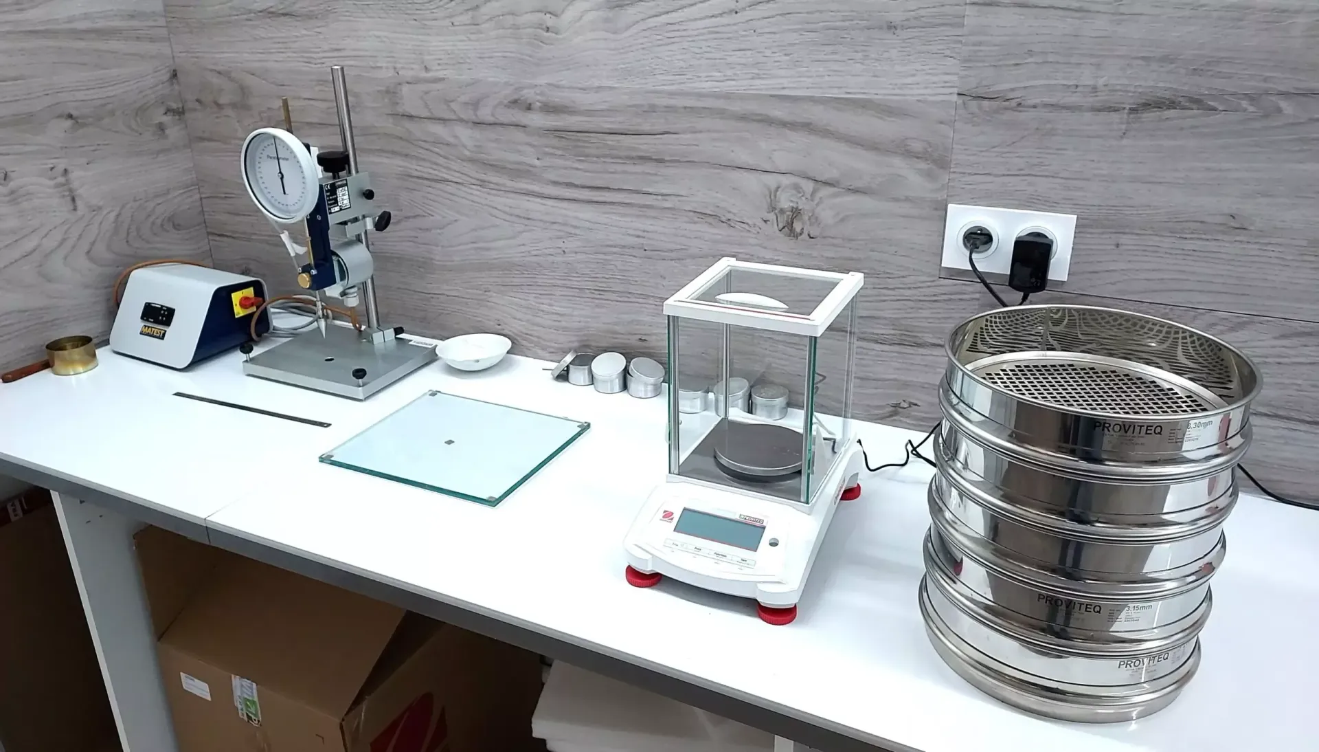 Espace de travail de laboratoire avec instruments scientifiques, dont une balance et des tamis.