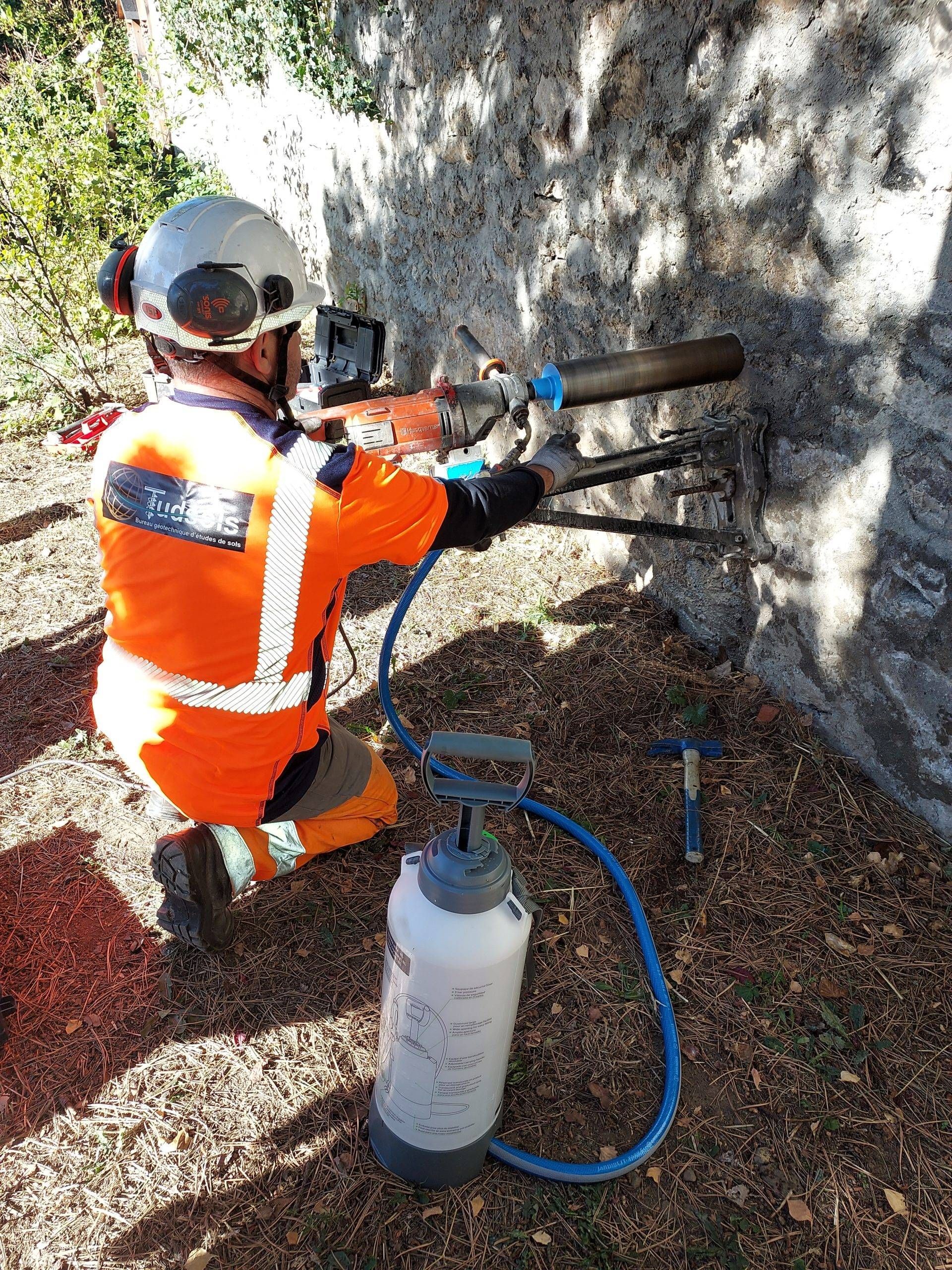 Une personne portant un équipement de sécurité orange perce la roche avec un équipement.