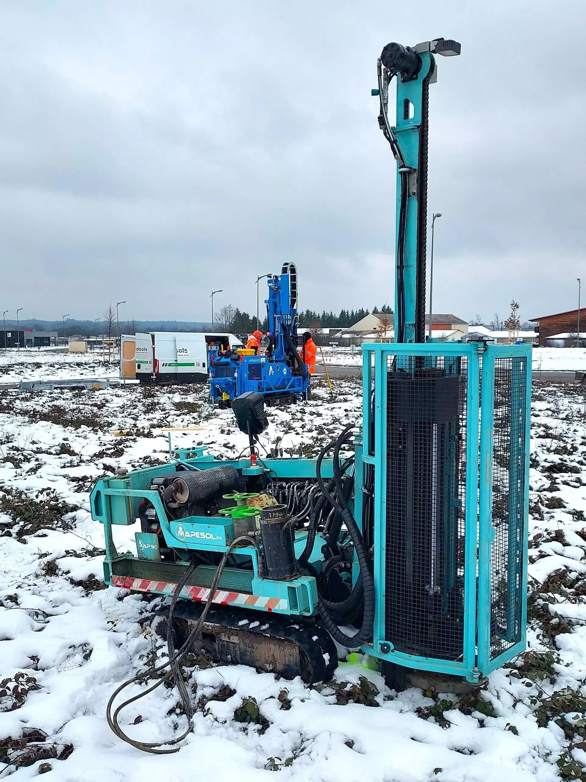 Une perceuse sur chenilles dans un champ enneigé, en fonctionnement.