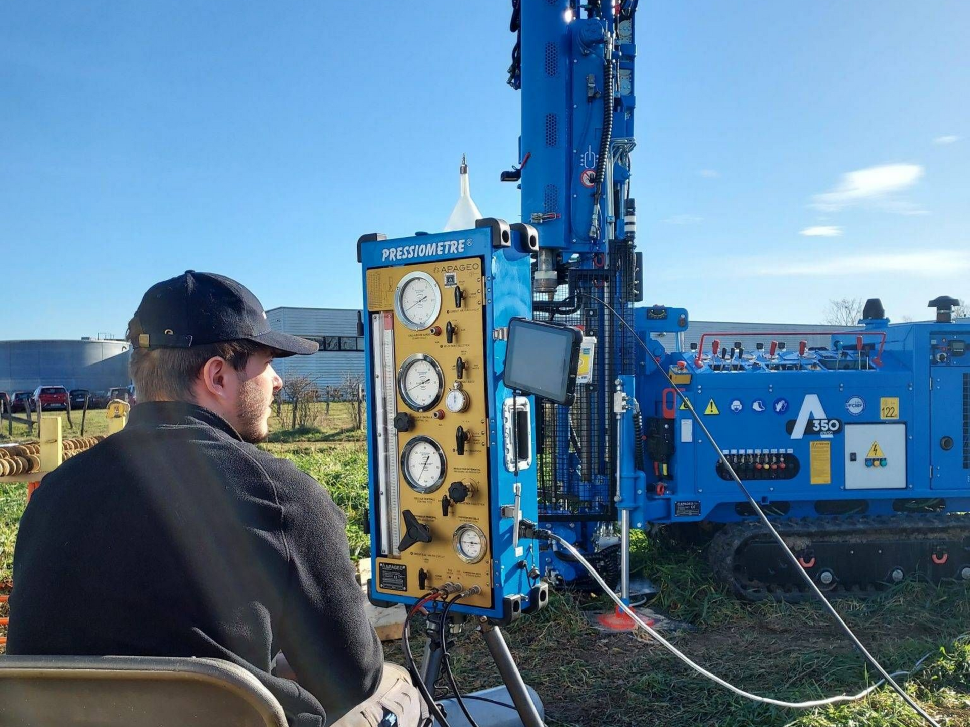 Personne manipulant une foreuse bleue à l'extérieur.