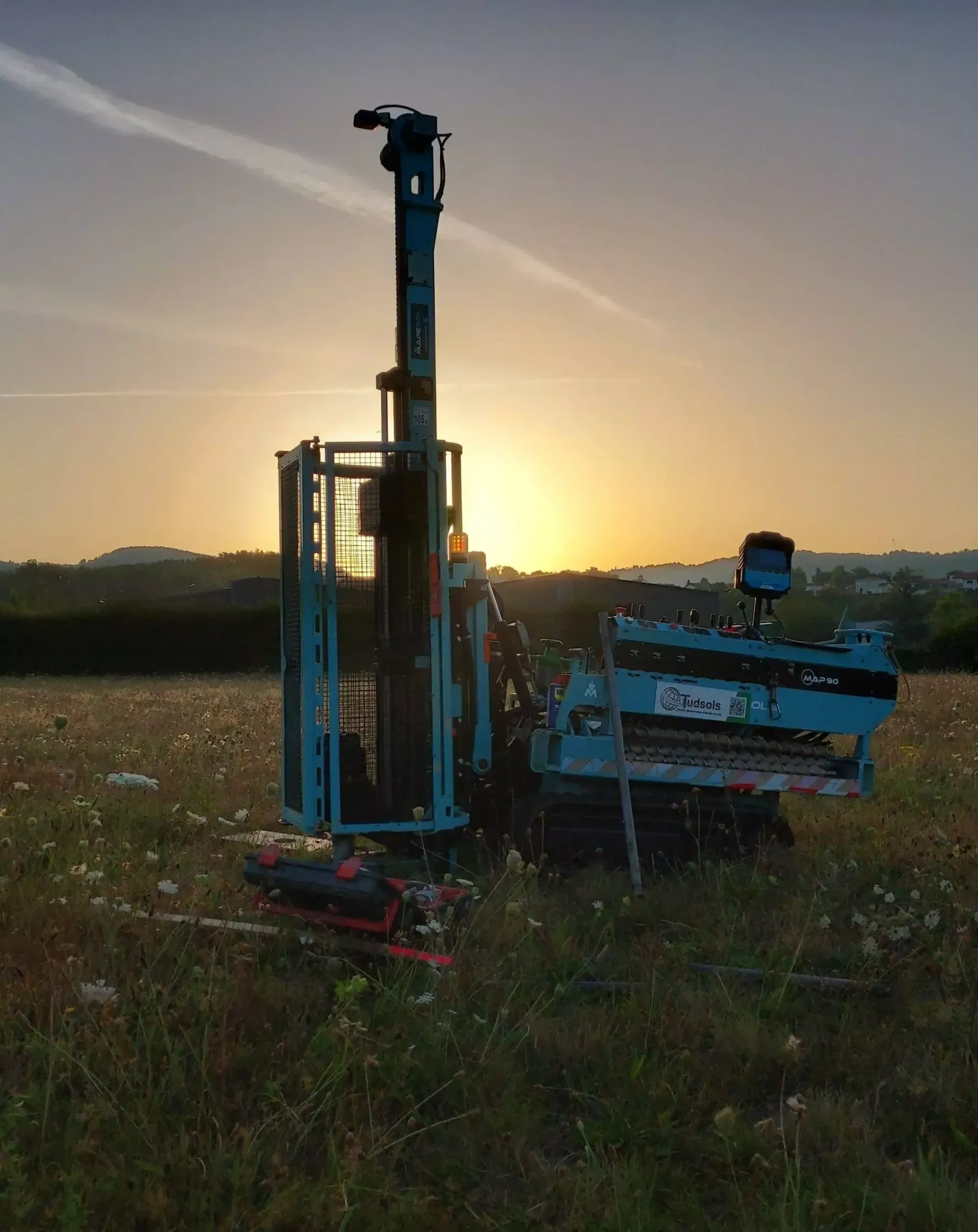Plateforme de forage dans un champ herbeux au coucher du soleil.