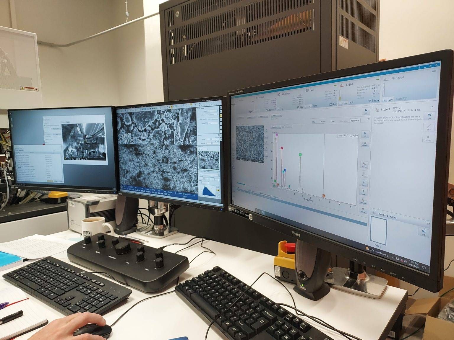 Trois écrans d'ordinateur affichant des données avec une main qui utilise une souris et deux claviers sur un bureau.