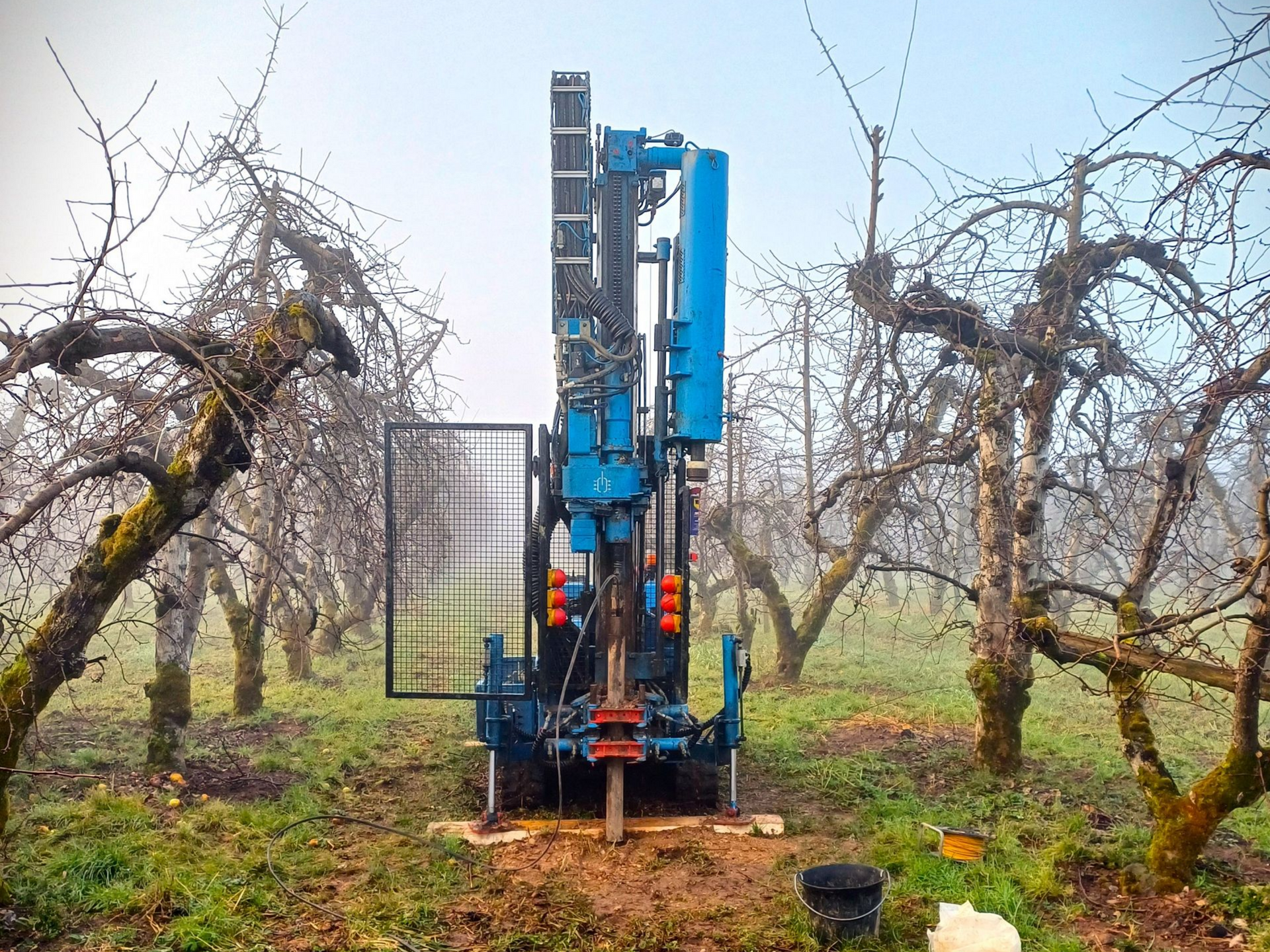 Foreuse bleue avec les arbres autour.