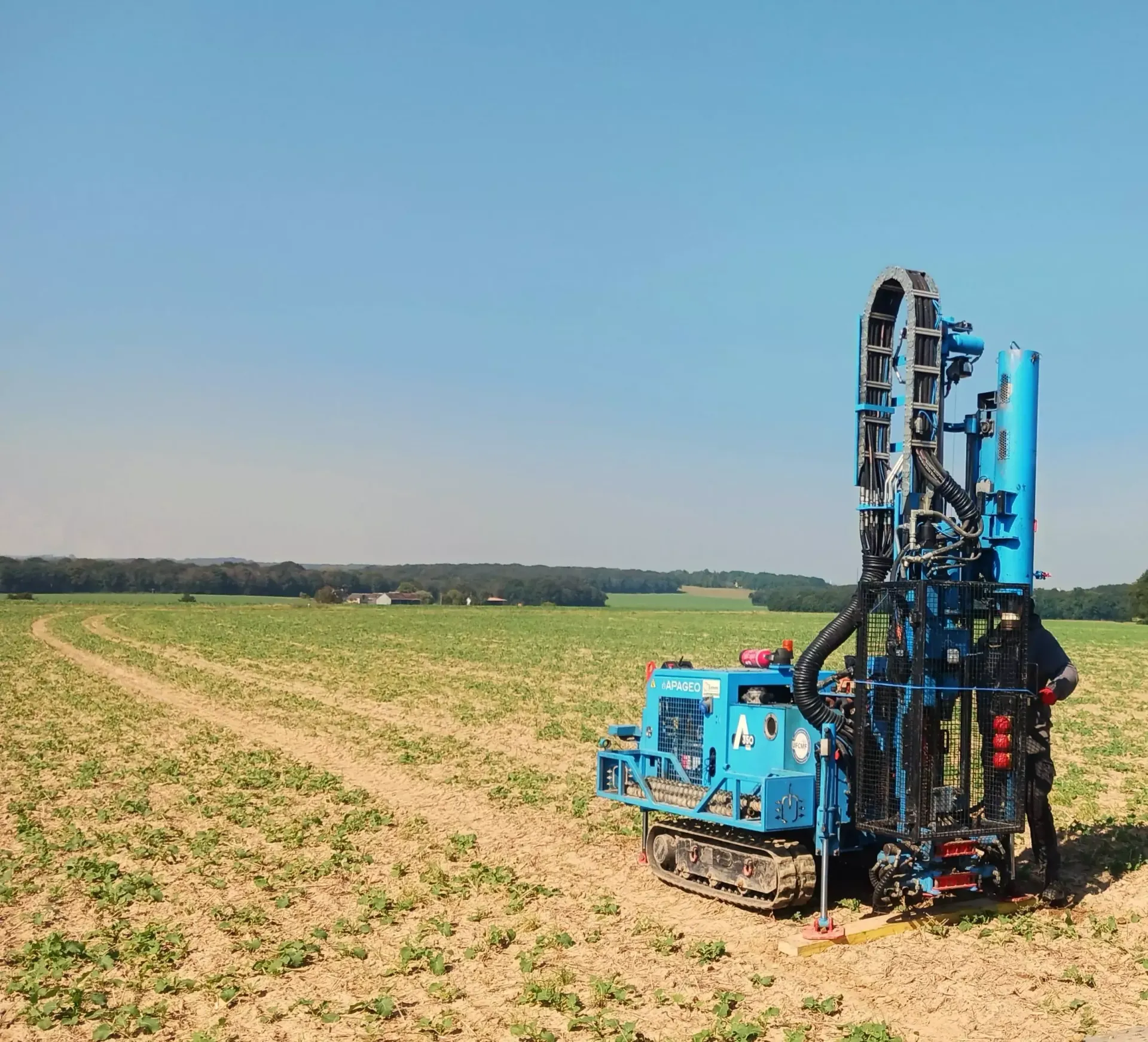 Une personne portant un équipement de sécurité orange perce un mur de pierre à l'aide d'une carotteuse.
