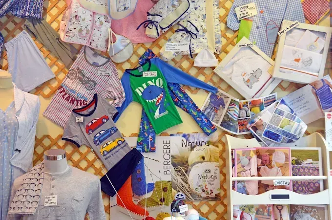 Pared expositora con ropa infantil variada, que incluye camisas, pantalones