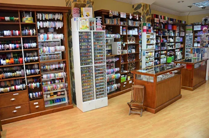 El interior de una tienda de manualidades con estanterías de madera repletas 
