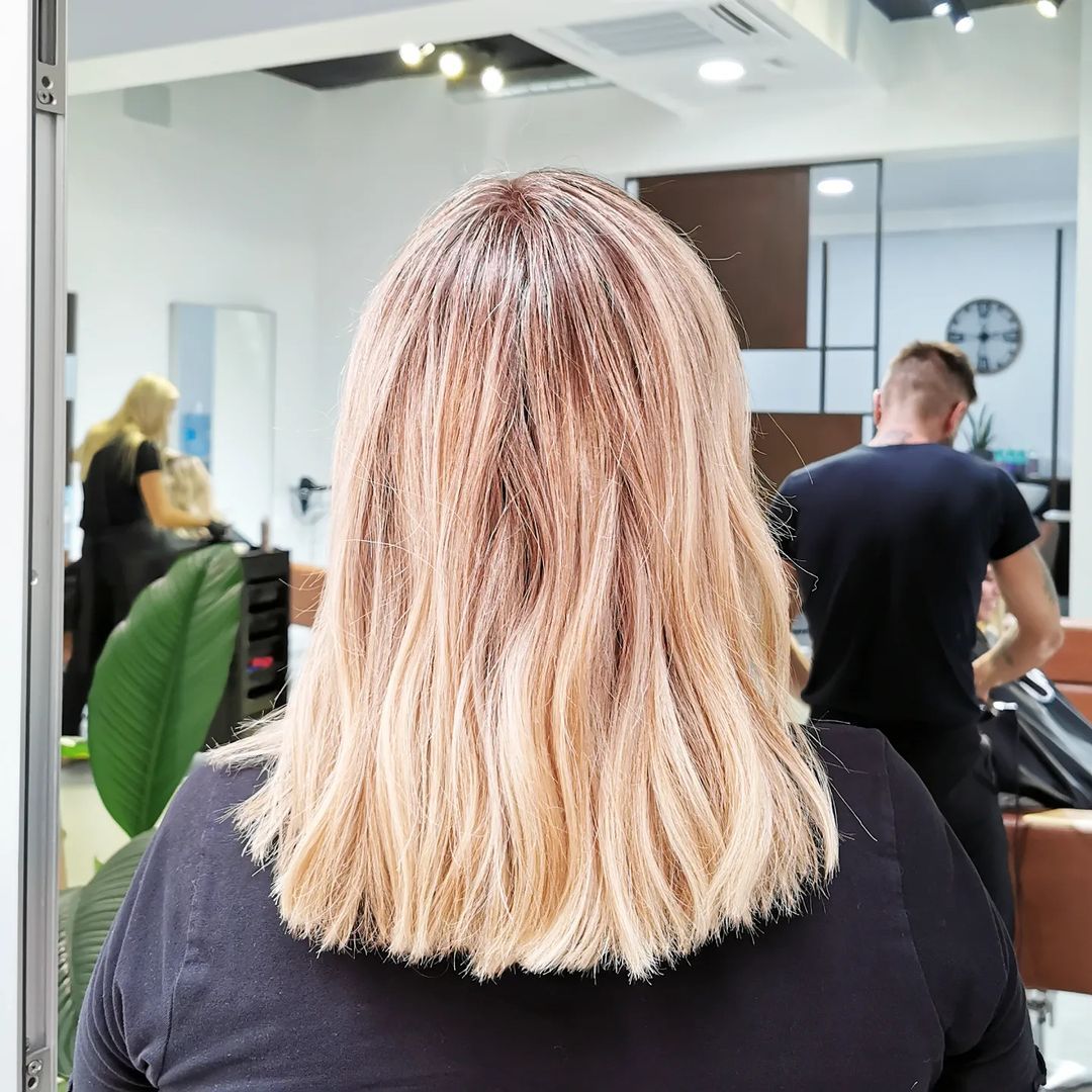 Una mujer con cabello rubio se tiñe el cabello en un salón.
