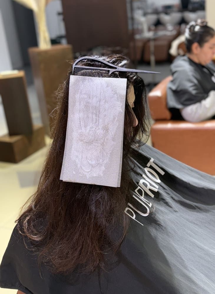 Una mujer con cabello rosado viste una camiseta blanca sin mangas y sonríe.