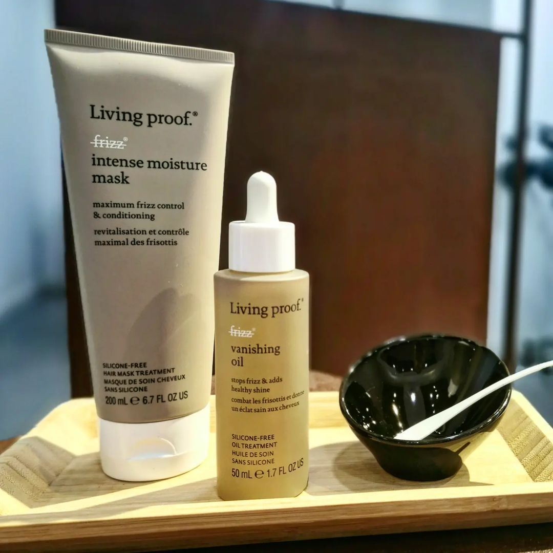 Dos botellas de productos Living Proof están en una bandeja de madera.