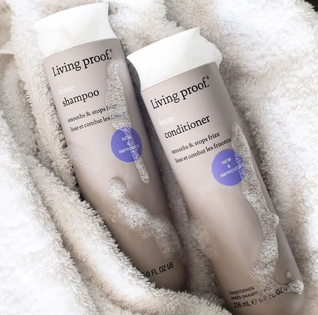 Dos botellas de champú y acondicionador Living Proof sobre una toalla.