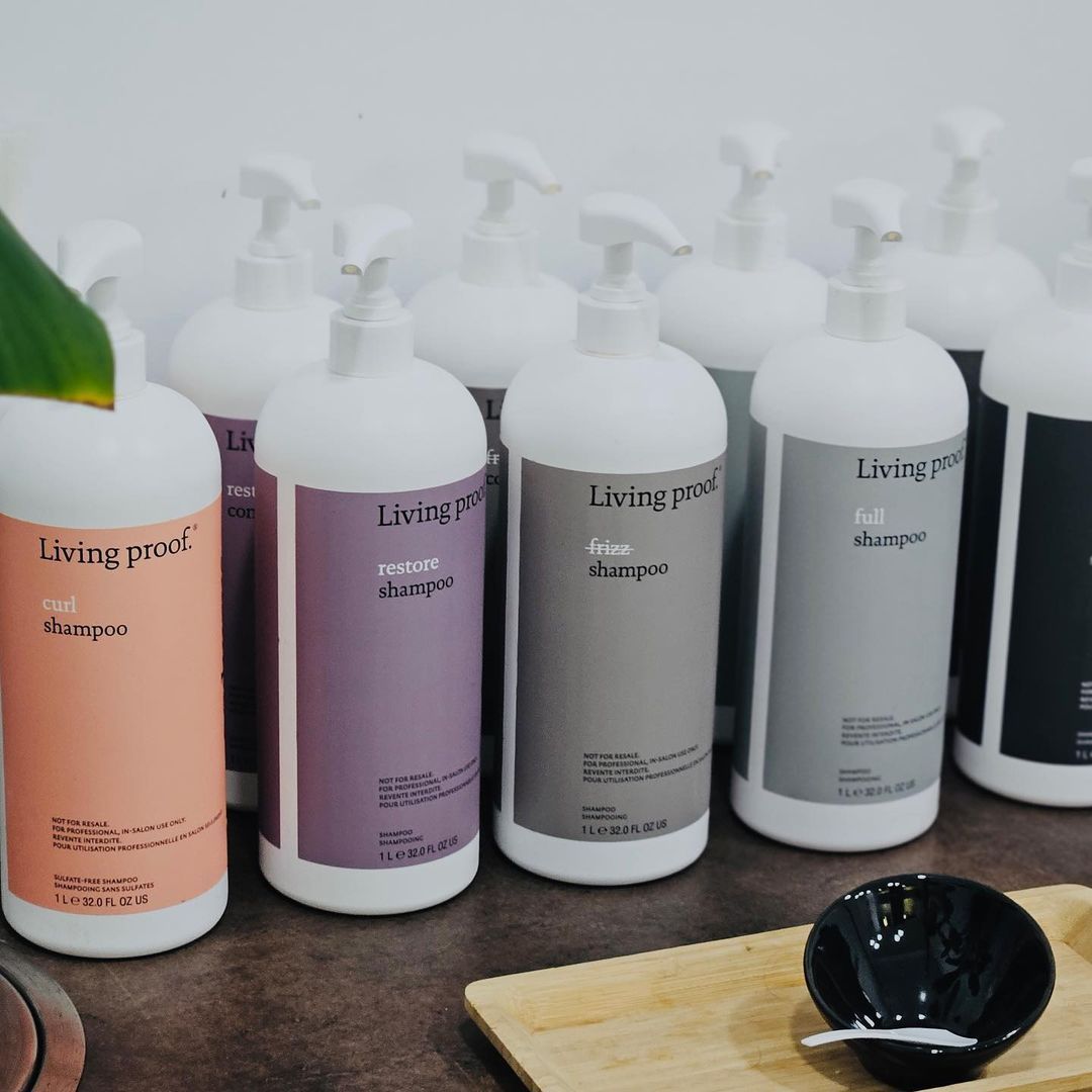 Varias botellas de productos Living Proof están alineadas sobre una mesa.