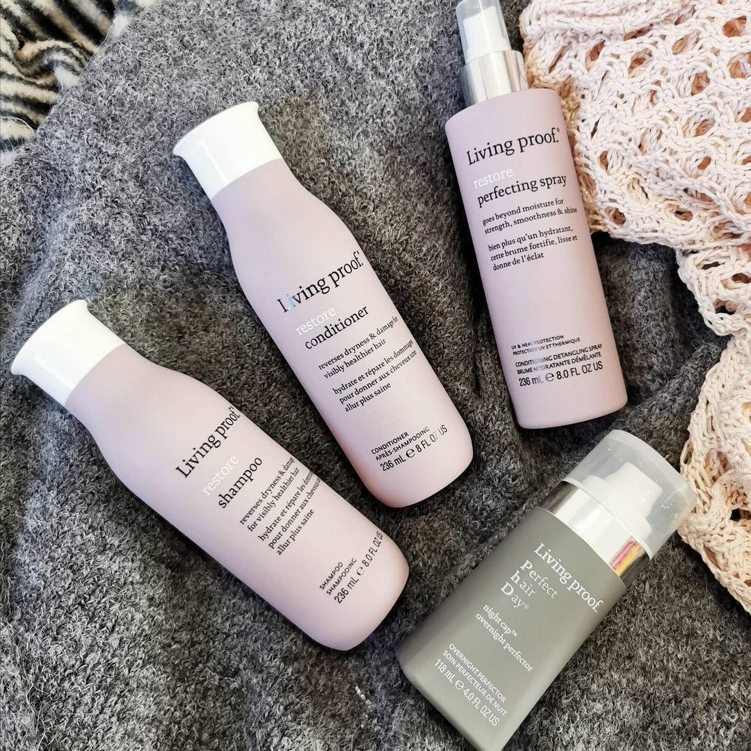 Tres botellas de productos para el cabello Living Proof están encima de una manta.