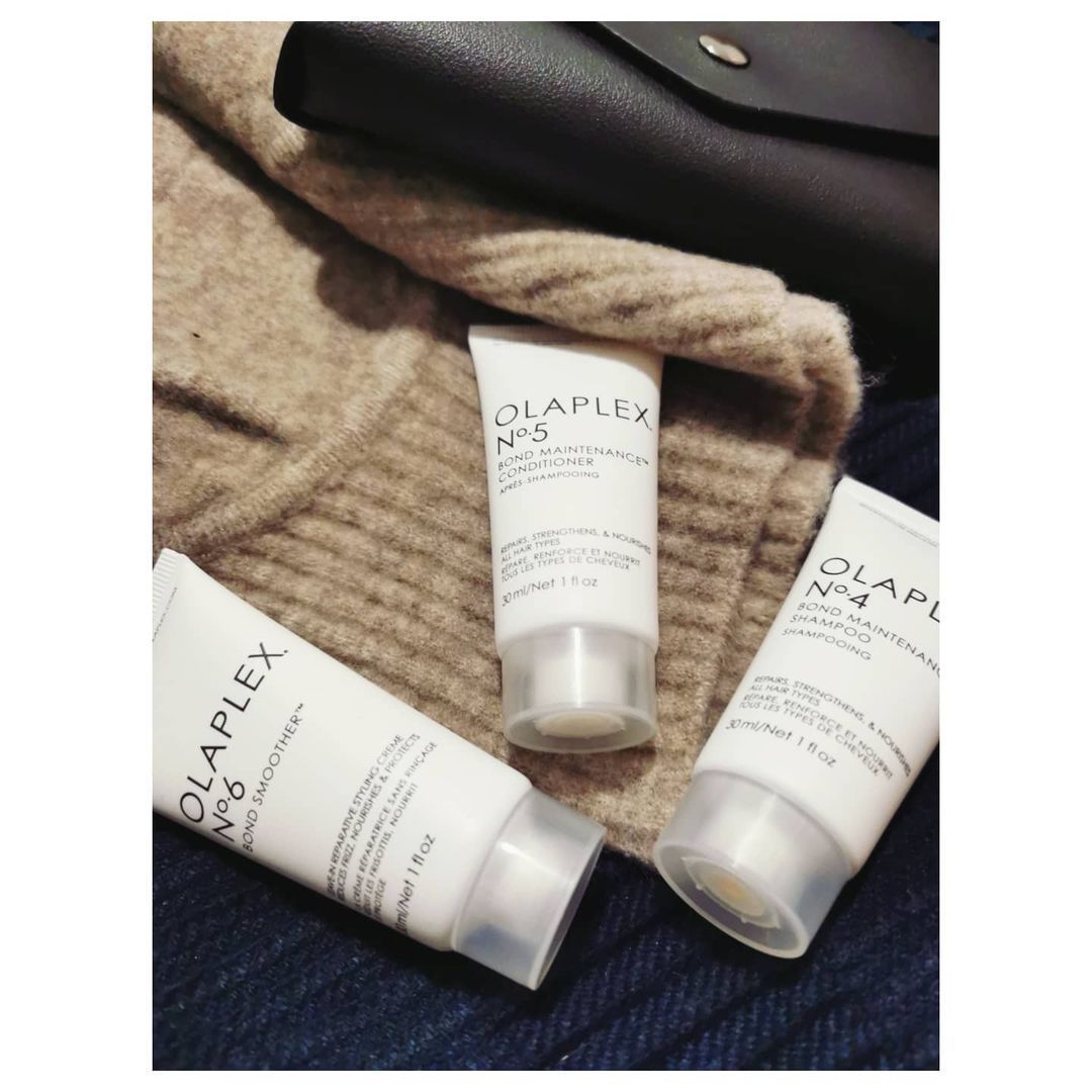 Hay tres botellas de olaplex sobre una manta.