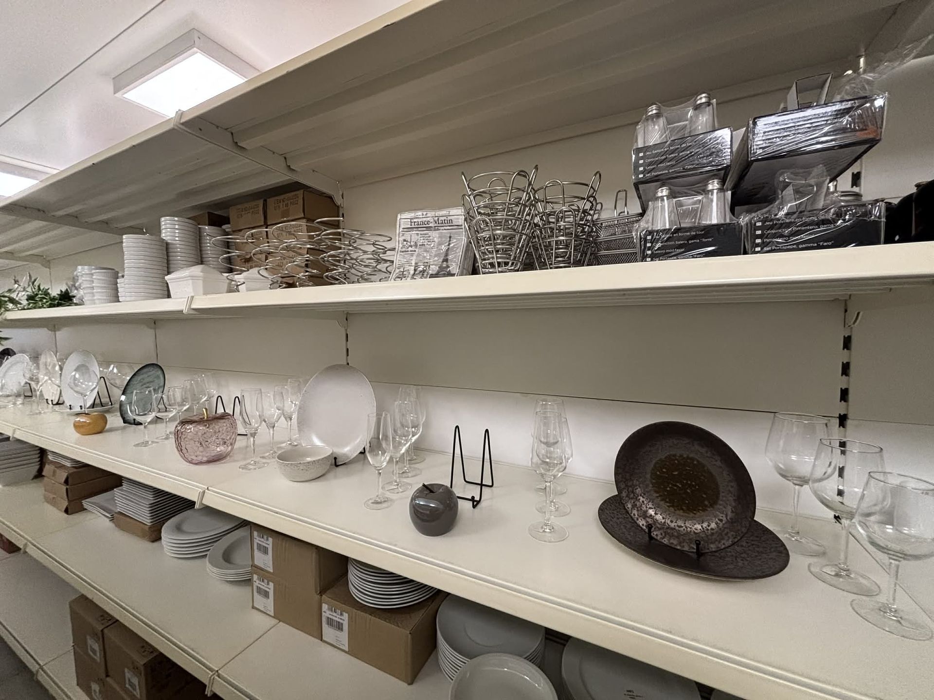 Des étagères dans un magasin rempli de vaisselle, de verrerie et d'objets décoratifs divers.