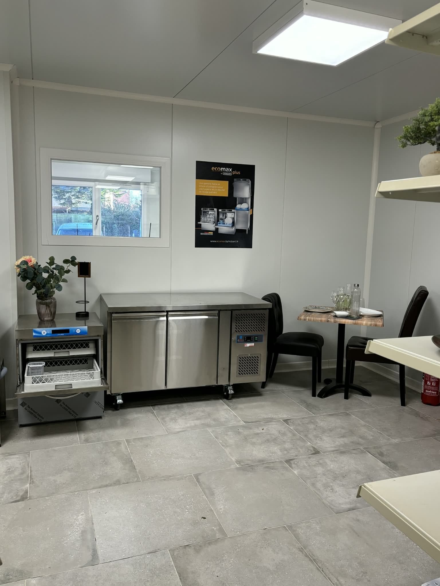 Une petite cuisine vide avec des appareils électroménagers en acier inoxydable, une table et une fenêtre.