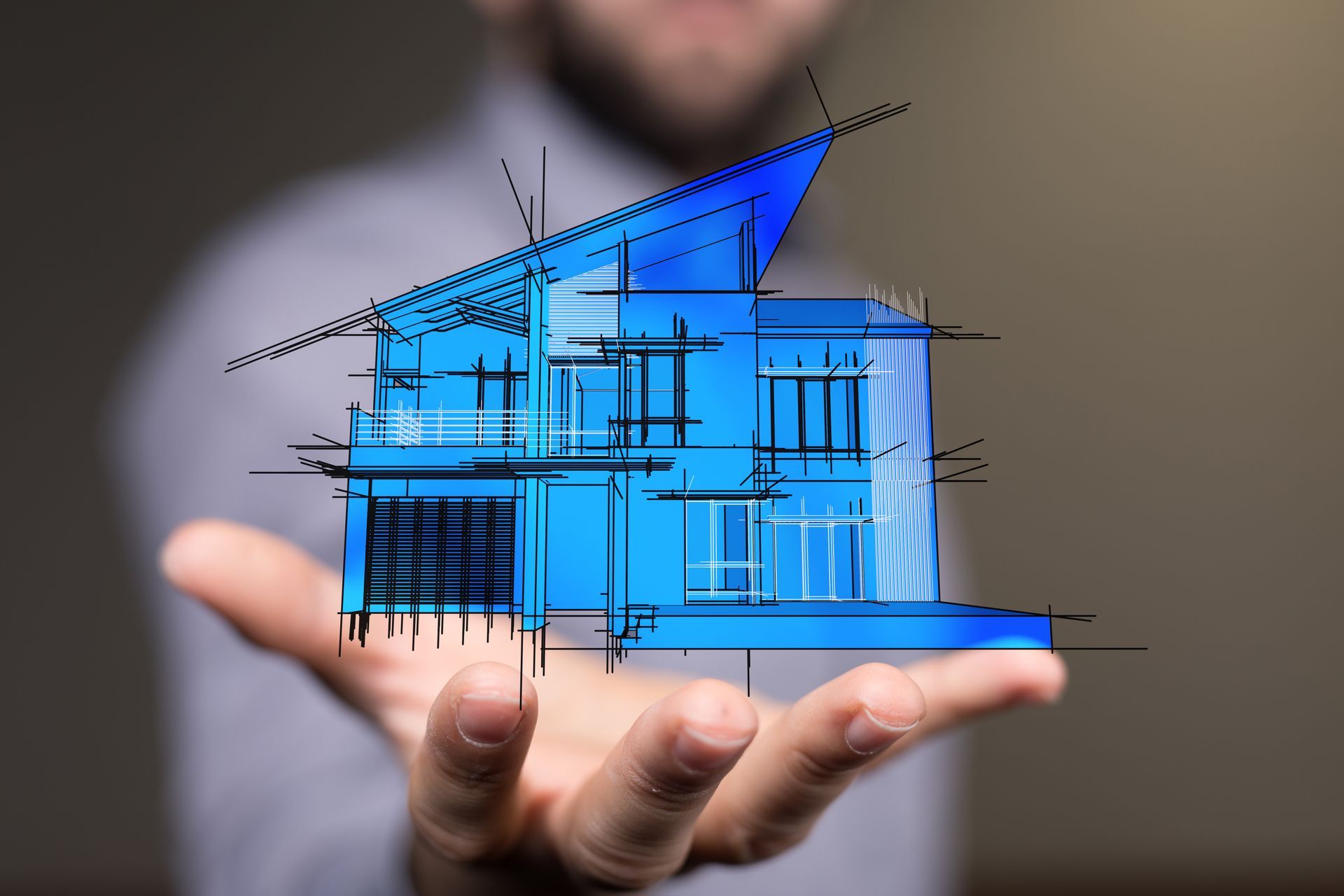 Une main tient un plan numérique bleu lumineux d'une maison, avec des lignes architecturales et des mesures.
