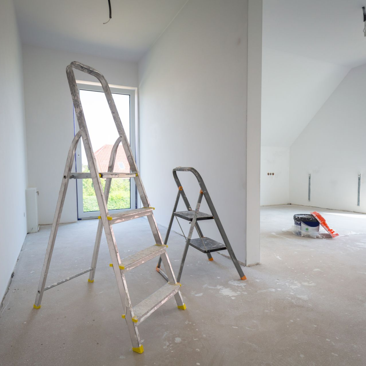 Découpe en bois en forme de maison à côté de pinceaux et d'un nuancier.