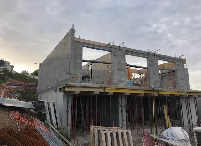 Bâtiment en béton partiellement construit, avec échafaudages et poteaux de soutien.