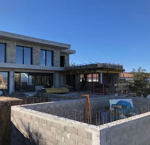 Maison moderne en construction avec murs en béton et un espace piscine.