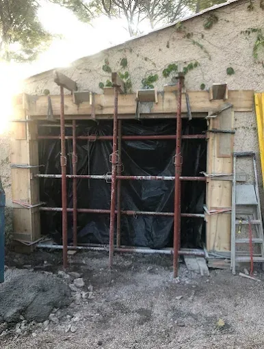 Échafaudages et échelles autour d'une ouverture sur un mur en construction.