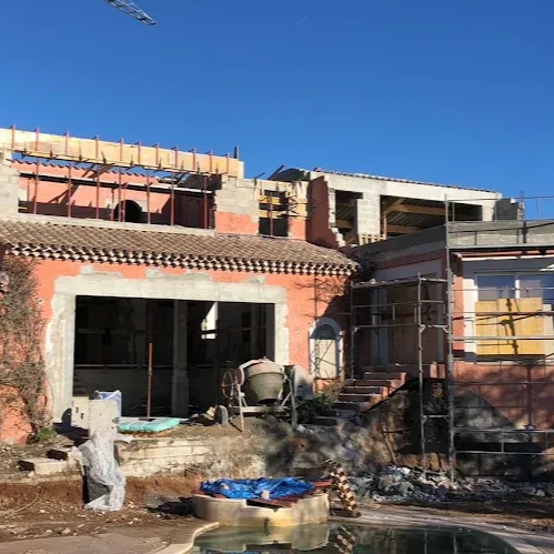 Maison en briques partiellement construite, avec des échafaudages.